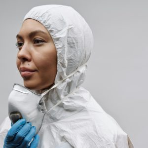 Woman wearing a protective suit and mask, emphasizing hygiene and safety during a pandemic.